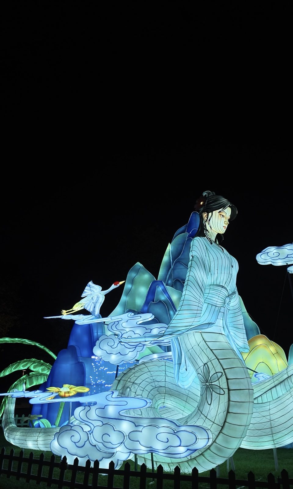 A lantern figure in flowing robes beside a flying crane and cloud lanterns