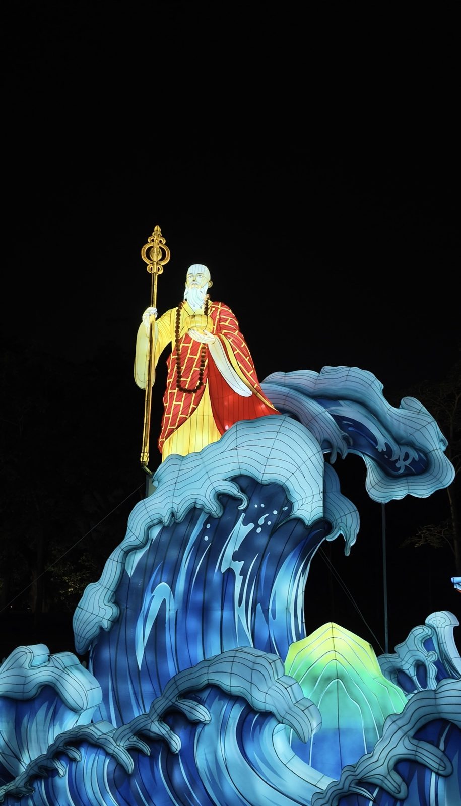 A monk lantern holding a staff above tall blue wave lanterns
